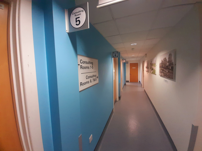 A corridor in the surgery with signs pointing to the consulting rooms